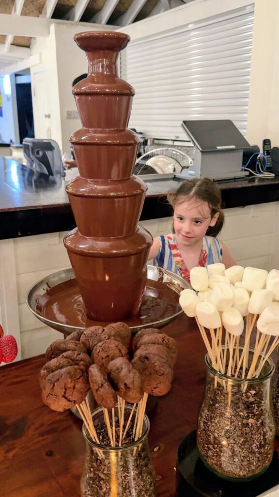 Young girl smiling at the chocolate fountain dessert station at Bonté restaurant, Sugar Beach Resort St. Lucia