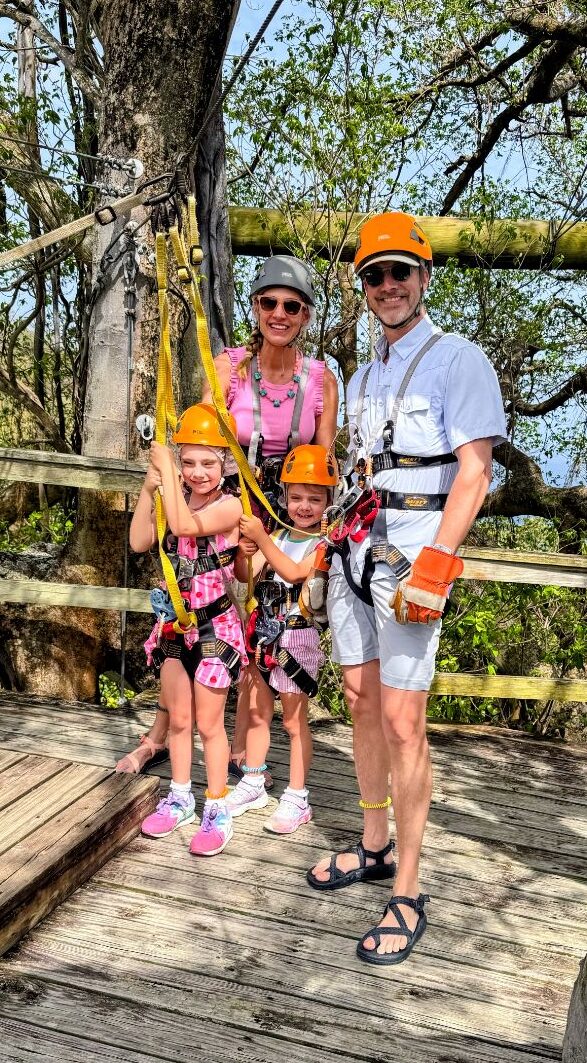 Two young girls wearing zipline harnesses at a rainforest canopy zipline in St. Lucia
