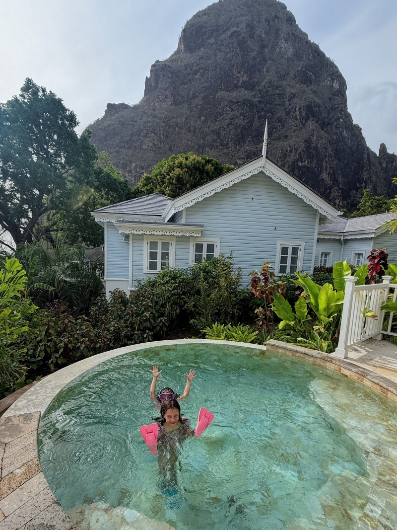 White plantation-style villa cottage at Sugar Beach Viceroy Resort with St. Lucia's Petit Piton rising behind it